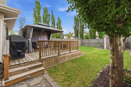 Expansive backyard featuring a wood-finish deck with railing, a detached gazebo structure, a manicured lawn, and a privacy fence - 20013 131 Avenue, Edmonton, AB 