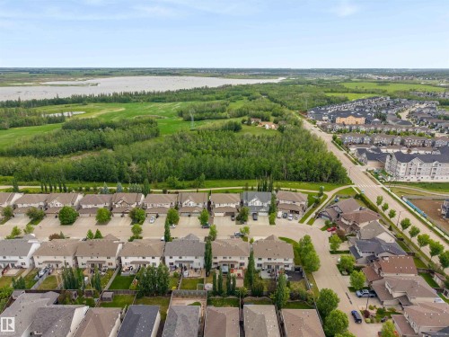 Expansive aerial view showcasing a residential neighborhood bordering a large body of water and natural green spaces - 20013 131 Avenue, Edmonton, AB 