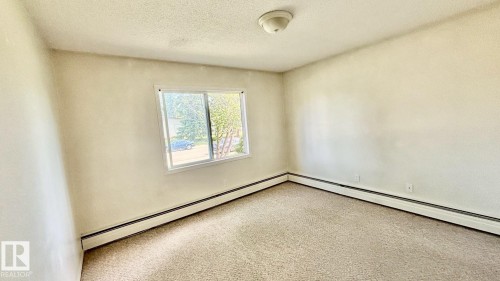 Room featuring neutral-toned carpeting, light-colored walls, and a sliding window - 203 11445 41 Avenue, Edmonton, AB 