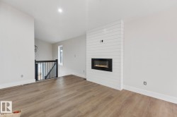 Living area featuring a modern linear fireplace with a shiplap surround, wood-finish flooring, recessed lighting, and a window providing natural light - 