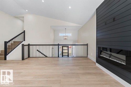 Spacious interior featuring wood-finish flooring, a contemporary fireplace with dark shiplap surround, and an open-concept layout with vaulted ceilings - 301 Fundy Way, Cold Lake, AB - Indoor Photo Showing Other Room