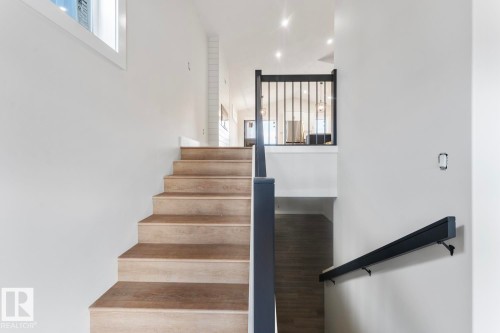 Contemporary staircase featuring wood-finish treads, a black iron spindle railing, and a minimalist wall-mounted handrail - 301 Fundy Way, Cold Lake, AB - Indoor Photo Showing Other Room