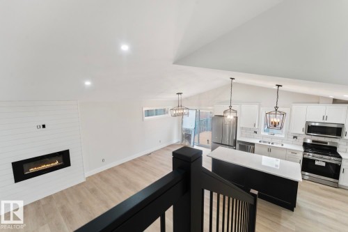 Open-concept living area featuring vaulted ceilings with recessed lighting, light wood-finish flooring, and a contemporary linear fireplace set into a shiplap accent wall - 301 Fundy Way, Cold Lake, AB - Indoor Photo Showing Kitchen With Stainless Steel Kitchen
