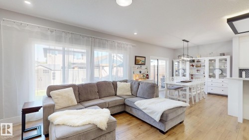 Open-concept living area with wood-finish flooring, recessed lighting, and a large window wall - 312 West Haven Drive, Leduc, AB 