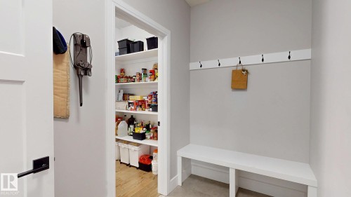 Entryway mudroom featuring a built-in bench, wall-mounted coat hooks, and an adjacent walk-in pantry - 312 West Haven Drive, Leduc, AB 