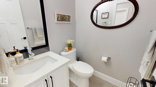 Bathroom featuring a white vanity with an integrated sink, polished chrome faucet, and quartz-finish countertop - 312 West Haven Drive, Leduc, AB 