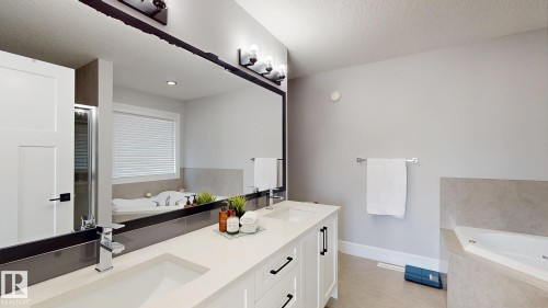Dual vanity with white cabinetry and dark hardware, featuring a light-toned countertop and dual undermount sinks - 312 West Haven Drive, Leduc, AB 