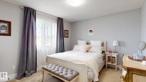 Carpeted bedroom featuring a large window, a ceiling-mounted light fixture, and light gray wall paint - 312 West Haven Drive, Leduc, AB 