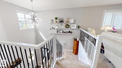 Staircase featuring dark spindle railings, a contemporary chandelier, and a window providing natural illumination - 