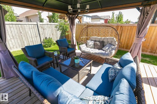 Covered wooden deck featuring a ceiling-mounted chandelier light fixture and privacy curtains - 312 West Haven Drive, Leduc, AB 