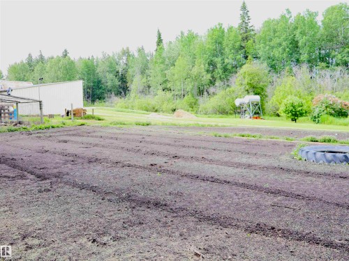 Cultivated land with prepared rows, featuring a metal-sided outbuilding and a background of mature trees - 58403 Rr 60, Rural Barrhead County, AB - Outdoor