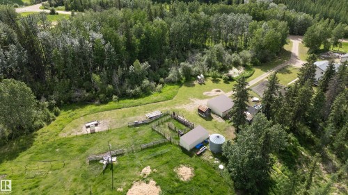 Expansive property featuring wooded areas, open grassy spaces, multiple outbuildings, fenced enclosures, and a visible driveway - 58403 Rr 60, Rural Barrhead County, AB - Outdoor With View