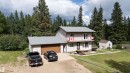 Two-story residence with light-toned siding, attached garage featuring a wood-finish door, and a second-story balcony - 58403 Rr 60, Rural Barrhead County, AB  - Outdoor 
