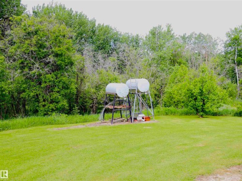 Expansive outdoor area featuring a lush green lawn and mature trees - 58403 Rr 60, Rural Barrhead County, AB - Outdoor