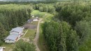 Expansive treed acreage featuring a primary residence with an attached garage, an unpaved driveway, multiple accessory structures, and cultivated garden plots - 58403 Rr 60, Rural Barrhead County, AB  - Outdoor With View 