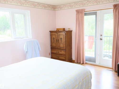 Bedroom featuring wood-finish flooring, a double window, and double glass doors leading to an outdoor balcony with metal railings - 58403 Rr 60, Rural Barrhead County, AB - Indoor Photo Showing Bedroom
