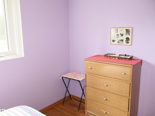 Room featuring a white-framed window, light purple walls, and wood-finish flooring - 58403 Rr 60, Rural Barrhead County, AB - Indoor Photo Showing Bedroom