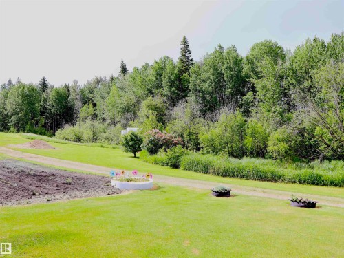 Expansive green lawn bordering a dense tree line - 58403 Rr 60, Rural Barrhead County, AB - Outdoor With View