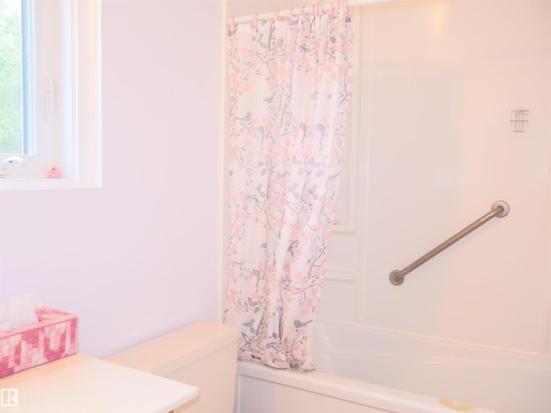 Bathtub and shower combination featuring a white surround and a grab bar - 58403 Rr 60, Rural Barrhead County, AB - Indoor Photo Showing Bathroom