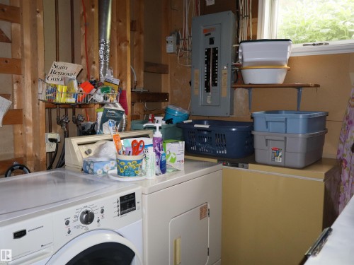 Dedicated laundry area featuring a front-loading washing machine, adjacent dryer, and utility sink - 58403 Rr 60, Rural Barrhead County, AB - Indoor Photo Showing Laundry Room