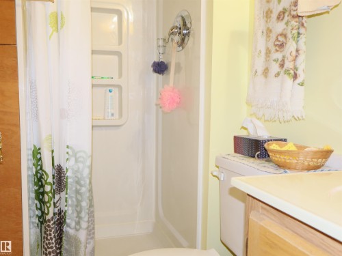 Bathroom featuring a light-colored vanity with a solid surface countertop, a toilet, and a white shower stall with built-in shelving - 58403 Rr 60, Rural Barrhead County, AB - Indoor Photo Showing Bathroom