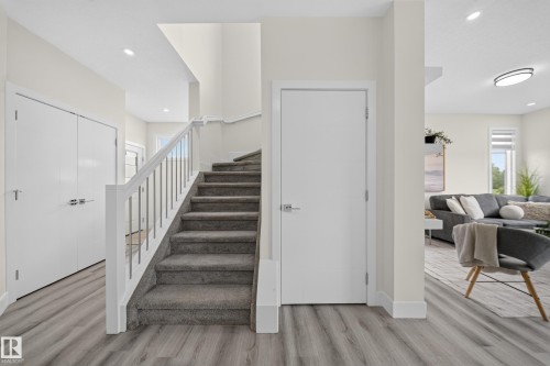 Staircase with carpeted treads and contemporary railing, featuring wood-finish flooring - 1099 Eaton Road, Edmonton, AB 