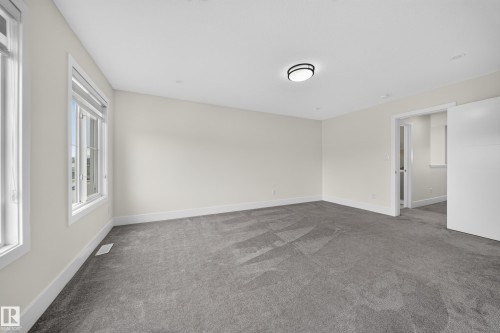 Spacious room featuring plush gray carpeting, neutral wall finishes, and expansive windows - 1099 Eaton Road, Edmonton, AB 