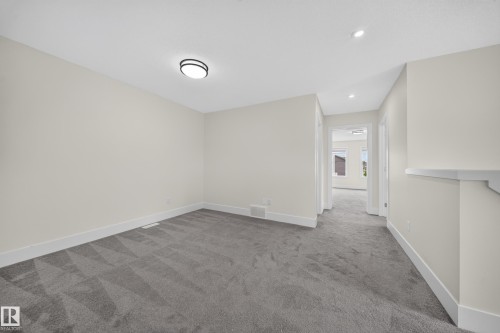 Spacious room featuring gray patterned carpet, light neutral walls, and crisp white baseboards - 1099 Eaton Road, Edmonton, AB 
