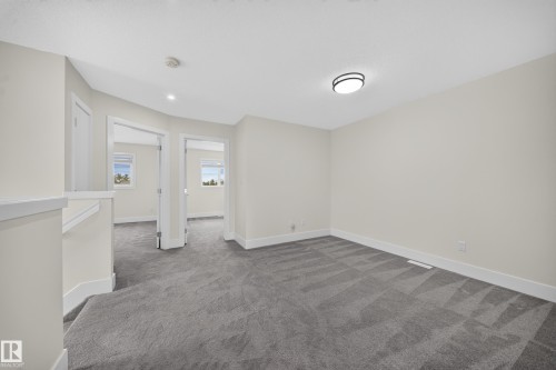 Carpeted upper-level landing featuring light-toned walls, white trim, and a contemporary flush-mount ceiling light - 1099 Eaton Road, Edmonton, AB 