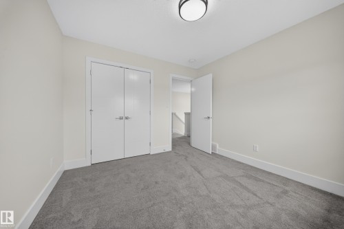 Carpeted room featuring light-colored walls, white trim, and a flush mount ceiling light fixture - 1099 Eaton Road, Edmonton, AB 