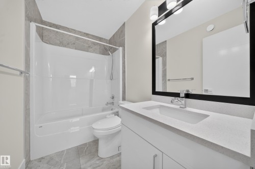 Modern bathroom featuring a white vanity with an integrated sink, a light-toned countertop, and a black-framed mirror with integrated lighting - 1099 Eaton Road, Edmonton, AB 