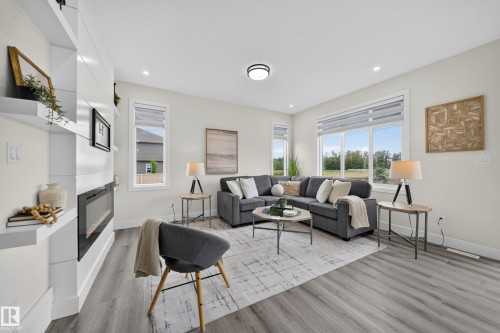 Bright living space featuring a built-in electric fireplace with surrounding shelving, multiple large windows, recessed lighting, and wood-finish flooring - 1099 Eaton Road, Edmonton, AB 