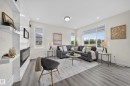Bright living space featuring a built-in electric fireplace with surrounding shelving, multiple large windows, recessed lighting, and wood-finish flooring - 1099 Eaton Road, Edmonton, AB 