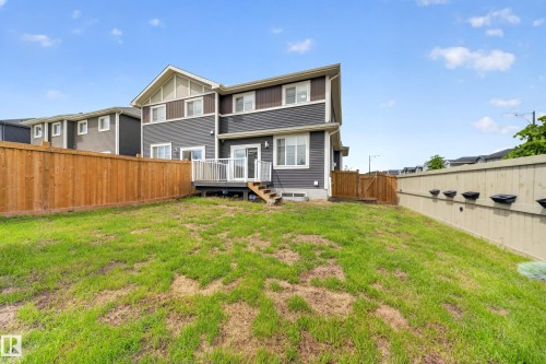 Rear exterior featuring a spacious deck with white railings, a fully fenced yard with wood privacy fencing, and direct access to the interior via a sliding glass door - 1099 Eaton Road, Edmonton, AB 