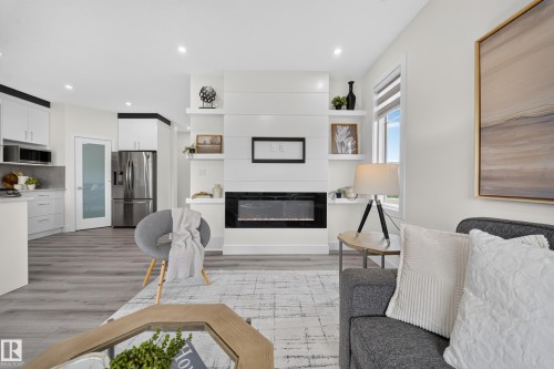 Living area featuring a floor-to-ceiling white shiplap fireplace surround with an inset electric fireplace, built-in shelving, and recessed lighting - 1099 Eaton Road, Edmonton, AB 