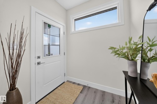 Entryway featuring a white door with divided light window, transom window, and wood-finish flooring - 1099 Eaton Road, Edmonton, AB 