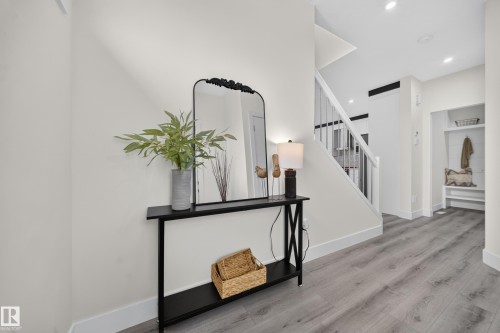 Entryway featuring wood-finish flooring, white baseboards, a built-in hall tree with shelving and hooks, and a staircase with white risers and dark handrails - 1099 Eaton Road, Edmonton, AB 