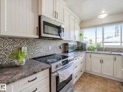 Kitchen featuring white cabinetry, mosaic tile backsplash, solid surface countertops, and a stainless steel over-the-range microwave - 