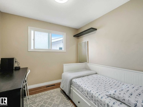 Bedroom featuring a single window with white trim, wood-finish flooring, and light-toned walls - 9207 169 Street, Edmonton, AB - Indoor Photo Showing Bedroom