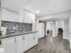 Kitchenette featuring white cabinetry, a mosaic tile backsplash, grey countertops, and wood-finish flooring - 
