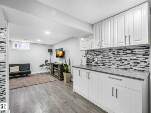 White cabinetry with stainless steel hardware, a gray countertop, and a mosaic tile backsplash - 9207 169 Street, Edmonton, AB - Indoor