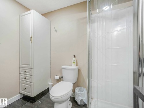 Three-piece bathroom featuring a stand-up shower with glass enclosure, white toilet, and tall white storage cabinetry - 9207 169 Street, Edmonton, AB - Indoor Photo Showing Bathroom