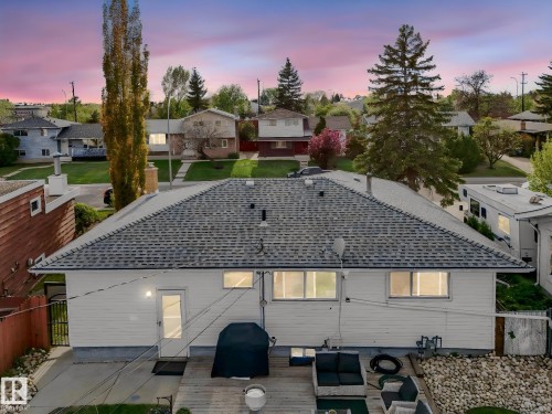 Rear exterior featuring a spacious wooden deck with stone landscaping, white siding, and a shingled roof - 9207 169 Street, Edmonton, AB - Outdoor