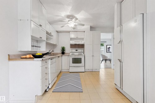 Kitchen featuring white cabinetry, light-toned countertops, tile flooring, built-in range, and a ceiling fan - 1131 Hooke Road, Edmonton, AB 