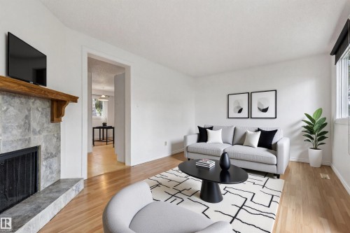 Living area featuring wood-finish flooring, a stone-tiled fireplace with a wood mantle, and a window with a black roller blind - 1131 Hooke Road, Edmonton, AB 
