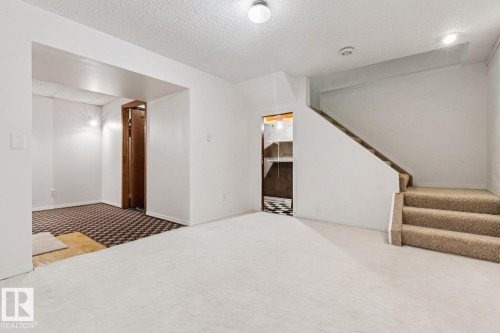 Finished room featuring a carpeted floor, white painted walls, and a textured ceiling - 1131 Hooke Road, Edmonton, AB 