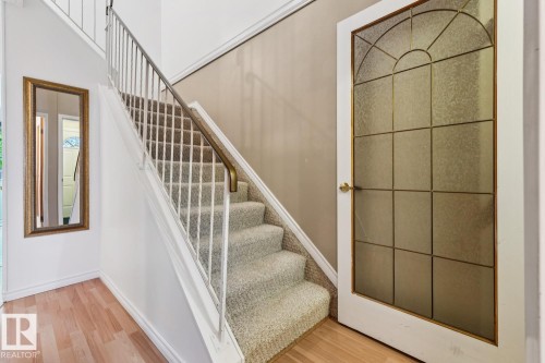 Carpeted staircase with white balusters and a brass handrail - 1131 Hooke Road, Edmonton, AB 