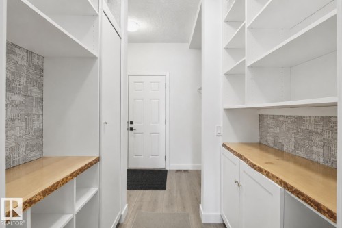 Entryway featuring white built-in cabinetry and shelving, live-edge wood countertops, and decorative wall paneling - 3234 Chernowski Way, Edmonton, AB 