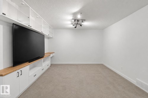 Integrated white cabinetry with wood-finish countertops and shelving - 3234 Chernowski Way, Edmonton, AB 