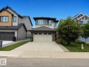 Contemporary exterior featuring a two-car garage, concrete driveway, and a front lawn with mature landscaping - 3234 Chernowski Way, Edmonton, AB 